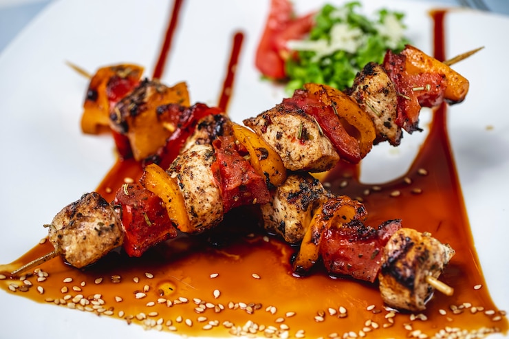 Foto gratuito vista lateral brochetas de pollo filete de pollo a la parrilla con pimientos rojos y amarillos salsa de condimento y semillas de sésamo en un plato