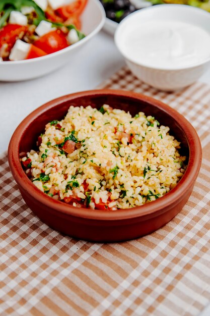 Vista lateral de bulgur con tomates en un tazón de madera