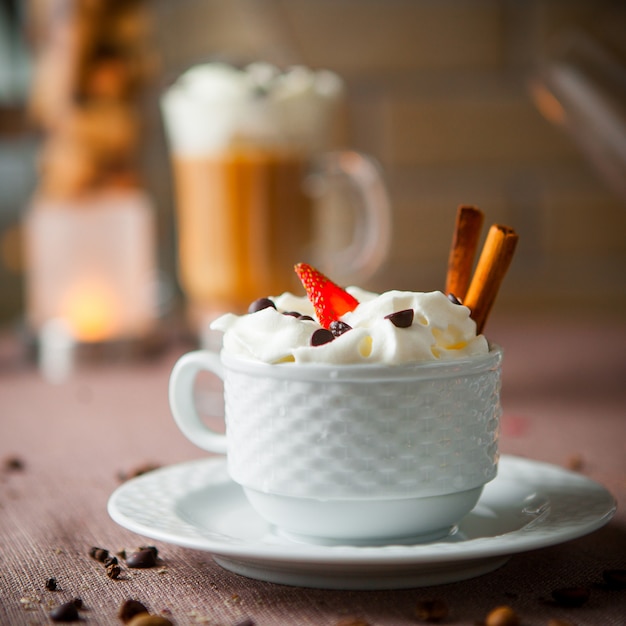 Vista lateral de café con leche con granos de café y velas en la taza blanca
