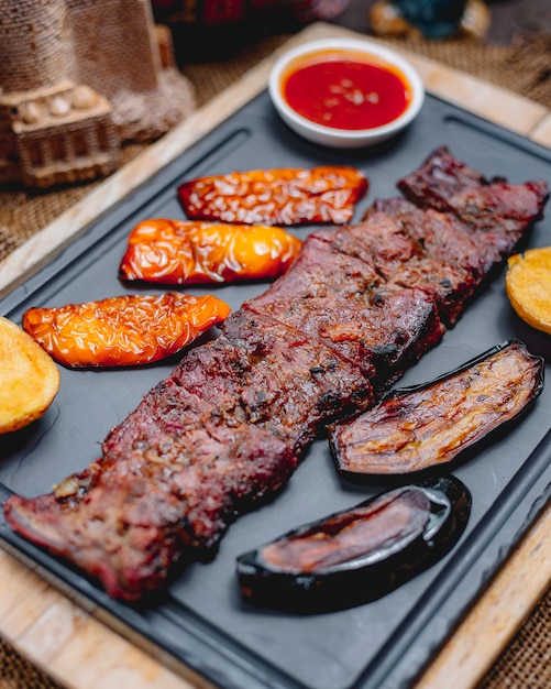 Foto gratuita vista lateral de carne asada langet con papas y verduras a la parrilla con salsas