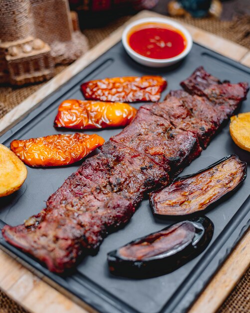 Vista lateral de carne asada langet con papas y verduras a la parrilla con salsas