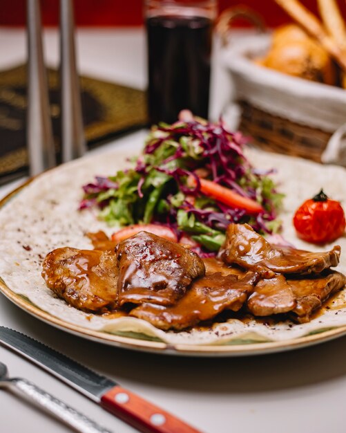 Vista lateral de carne de cordero a la parrilla con salsa de lechuga, col roja y tomate en pita