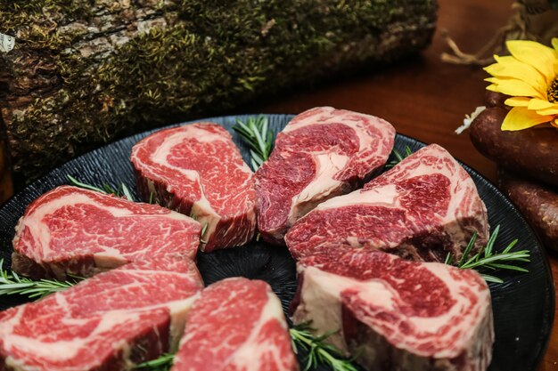 Vista lateral de carne cruda de carne marmolada con romero en un stand