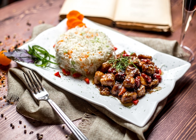 Vista lateral de carne frita en salsa con frutos secos y arroz