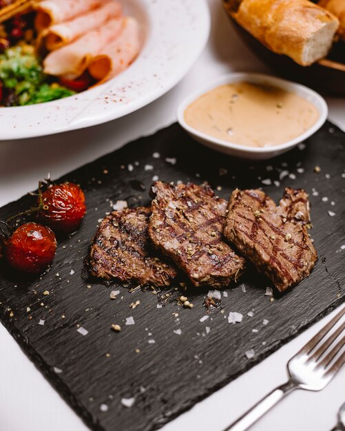 Vista lateral de carne a la parrilla con salsa de pan de tomate sal de hierbas