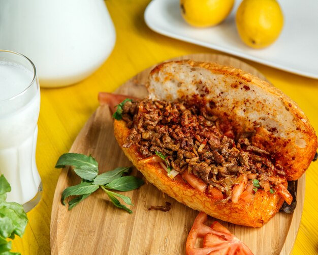 Foto gratuita vista lateral de carne picada con verduras en pan servido con tomates frescos y limón sobre tabla de madera