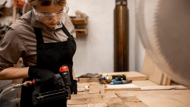 Foto gratuita vista lateral del carpintero femenino con grapadora neumática