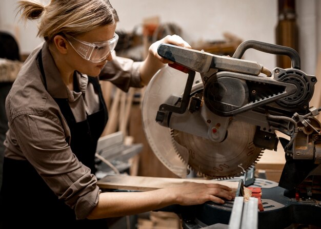 Vista lateral del carpintero femenino con herramientas y gafas de seguridad