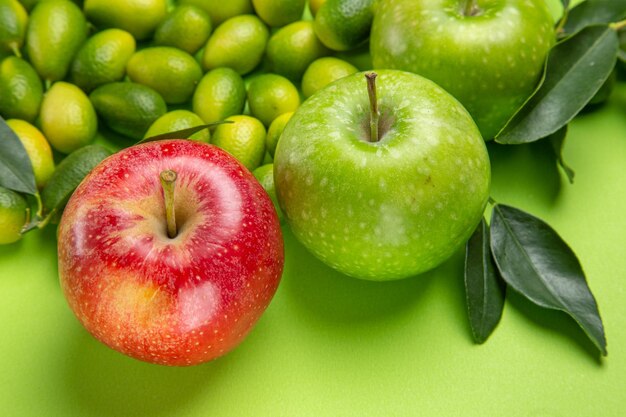 Vista lateral de cerca frutas manzanas rojas y verdes frutas cítricas con hojas