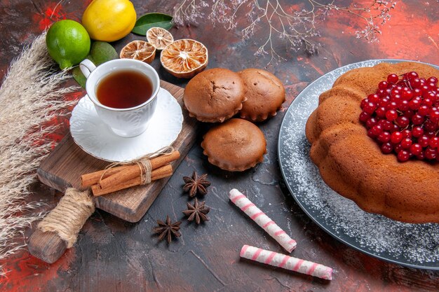 Vista lateral de cerca una taza de té un pastel con grosellas rojas anís estrellado una taza de té en el tablero