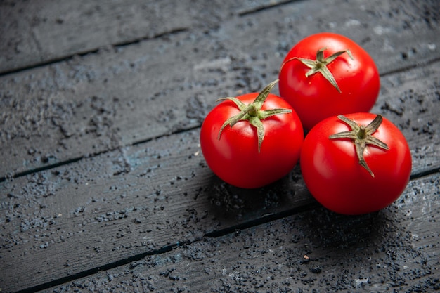 Vista lateral de cerca los tomates en la mesa tomates rojos en el lado derecho de la mesa gris de madera