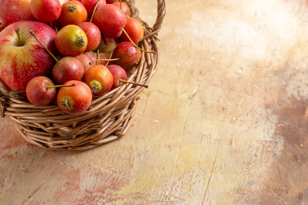 Vista lateral cercana bayas manzanas y bayas en la canasta de madera sobre la mesa de crema