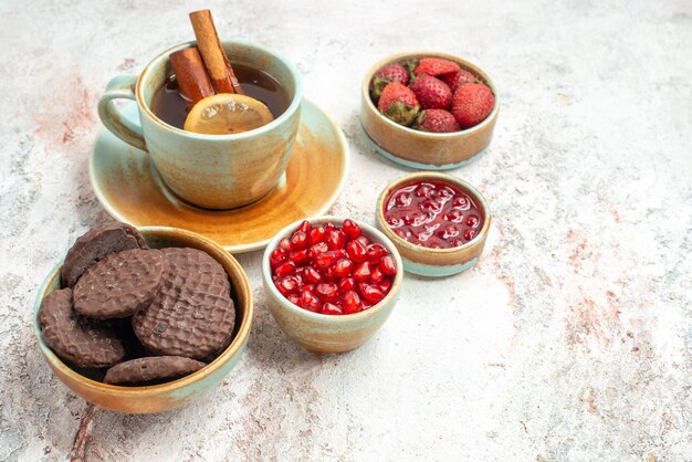 Vista lateral cercana bayas y té una taza de té con limón y canela galletas mermelada de bayas