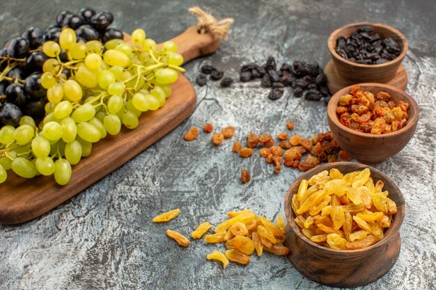 Vista lateral cercana cuencos de frutos secos de los coloridos frutos secos apetitosos uvas en el tablero