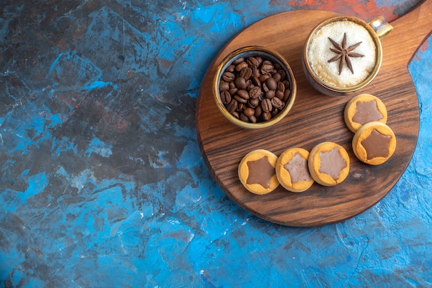 Vista lateral cercana dulces galletas granos de café una taza de café en la tabla de madera