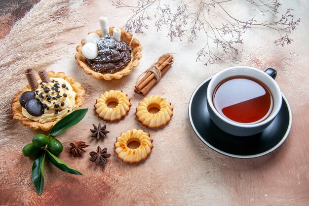 Vista lateral cercana dulces una taza de té cupcakes galletas cítricos anís estrellado