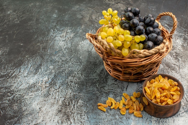 Vista lateral cercana frutas la canasta de las apetitosas uvas junto al cuenco de frutos secos