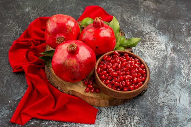 Vista lateral cercana frutas granadas rojas en la tabla de cortar sobre el mantel rojo