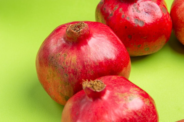 Vista lateral cercana frutas manzanas granadas en la superficie verde