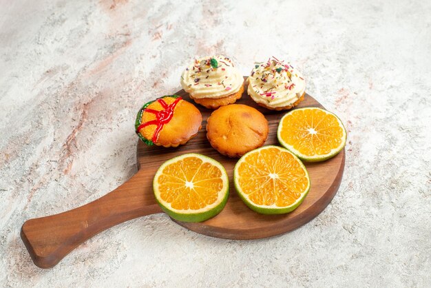 Vista lateral cercana galletas apetitosas rodajas de naranja y galletas en la placa de cocina de madera sobre la mesa