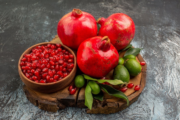 Vista lateral cercana granadas granadas maduras y frutas cítricas con hojas en el tablero