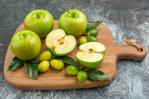 Vista lateral cercana manzanas cítricos manzanas con hojas en el tablero