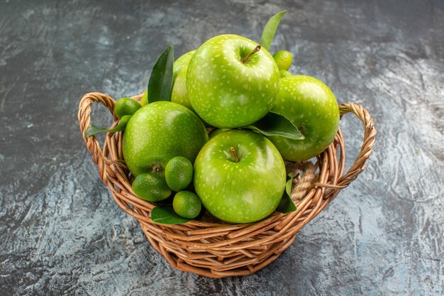 Vista lateral cercana manzanas manzanas verdes con hojas de frutas cítricas en la canasta