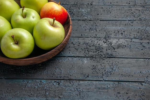 Vista lateral cercana manzanas en un tazón un tazón de manzanas verde-rojo-amarillo en el lado izquierdo de la mesa de madera