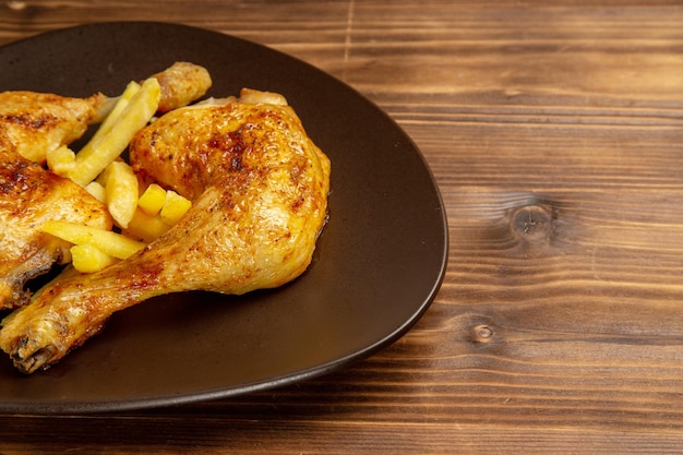 Vista lateral cercana de muslos de pollo plato de apetitosos muslos de pollo y papas fritas en el lado izquierdo de la mesa