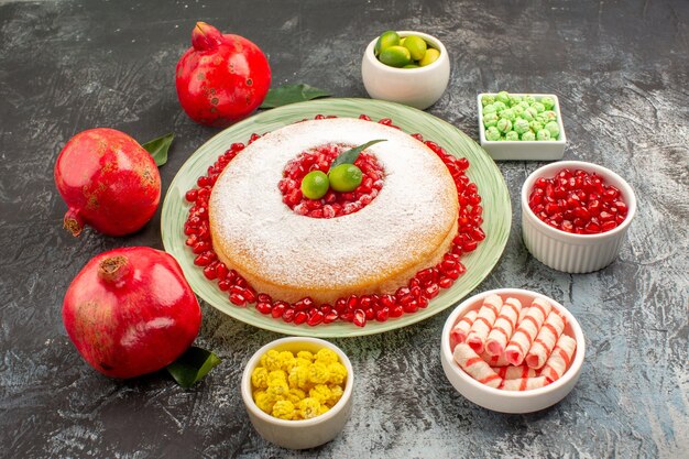 Vista lateral cercana pasteles dulces un plato de pastel granadas tazones de frutas cítricas caramelos coloridos