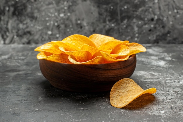 Vista lateral cercana de patatas fritas en un tazón sobre la mesa gris oscuro con fondo gris oscuro