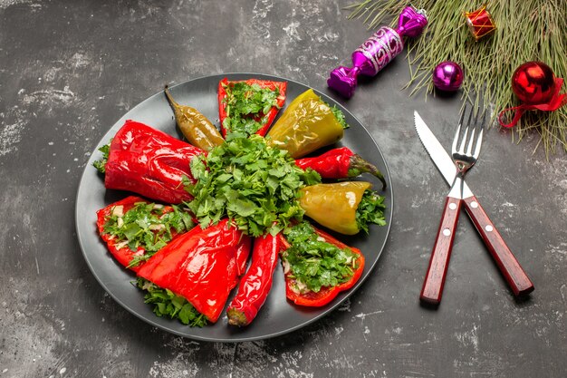 Vista lateral cercana plato pimientos con hierbas cuchillo tenedor caramelos juguetes de Navidad