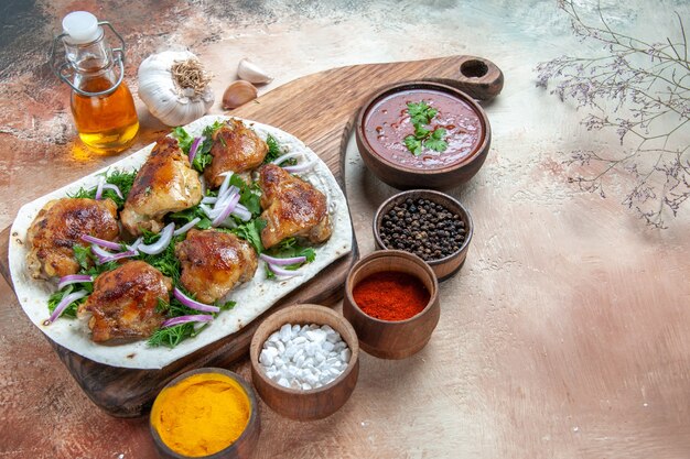 Vista lateral cercana pollo pollo con hierbas de cebolla en lavash botella de salsa de aceite especias de ajo