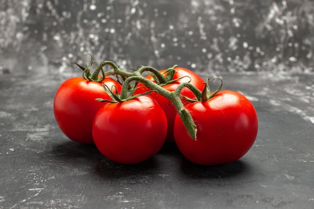 Vista lateral cercana tomates apetitosos tomates con tallos sobre el fondo negro