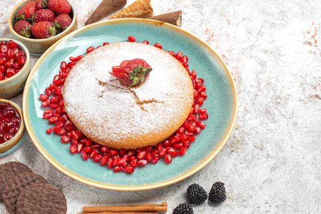 Vista lateral cercana de la torta de palitos de canela torta con bayas, galletas y bayas diferentes