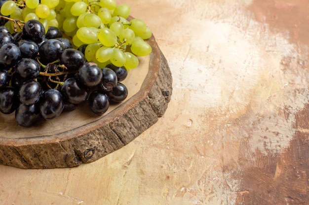 Foto gratuita vista lateral cercana uvas uvas negras y verdes sobre la plancha de madera