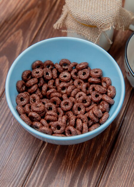 Vista lateral de cereales en un tazón con crema sobre superficie de madera