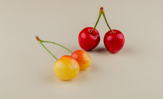 Vista lateral de cerezas maduras rojas y amarillas aisladas en blanco