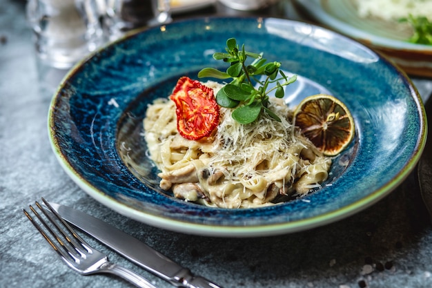 Vista lateral champiñones cremosos hongos fettuccine sal pimienta ajo pasta queso y tomate seco en un plato