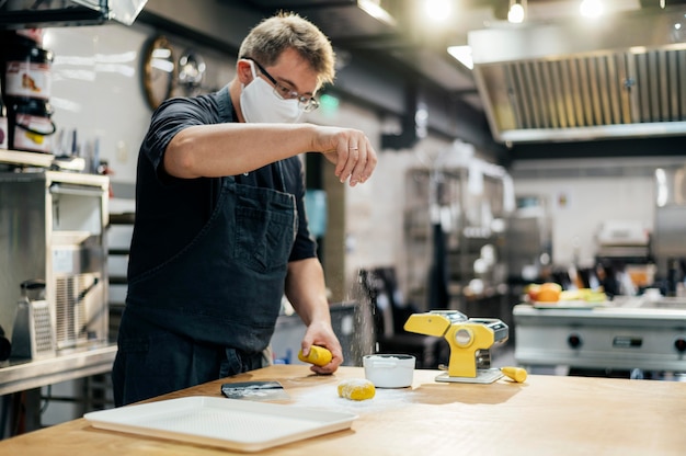 Vista lateral del chef masculino con pasta de condimento de máscara