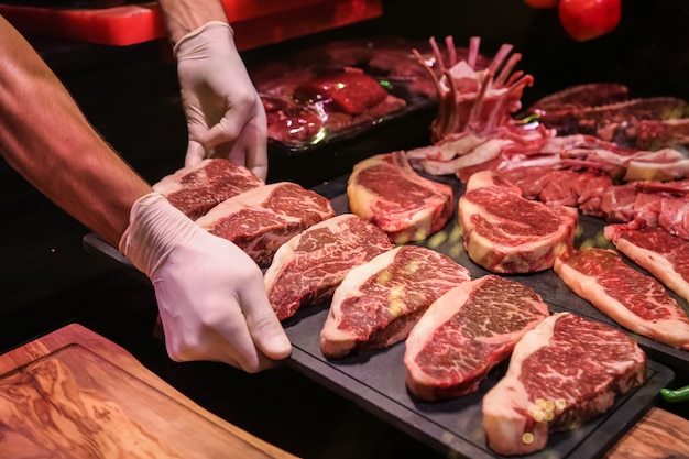 Vista lateral, el chef prepara carne cruda de mármol para filetes en un soporte