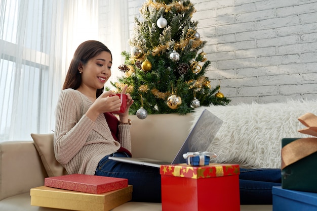 Vista lateral de una chica asiática comprando en línea en Nochebuena