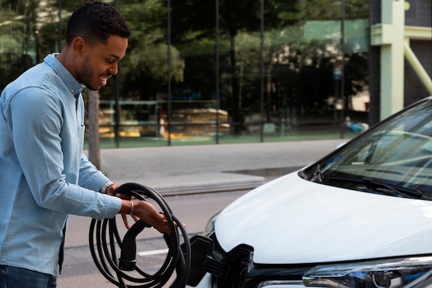 Foto gratuita vista lateral del coche eléctrico de carga del hombre sonriente