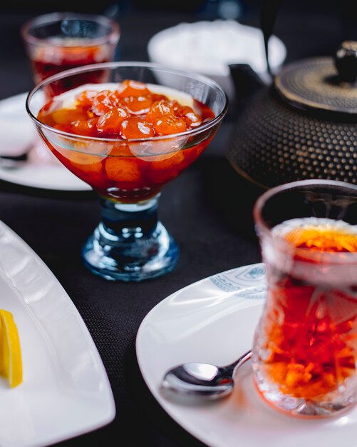 Vista lateral de la cocina azerbaiyana mermelada de cerezas blancas en un jarrón de vidrio servido con té