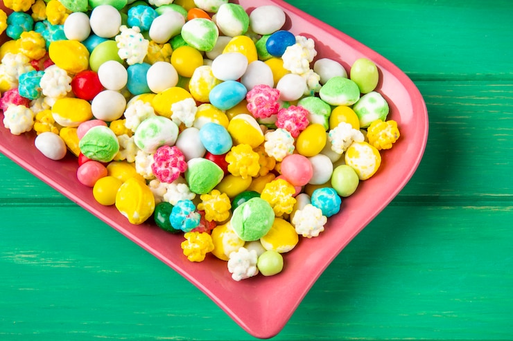 Foto gratuito vista lateral de coloridos dulces de azúcar dulce en una bandeja de cerámica sobre fondo verde