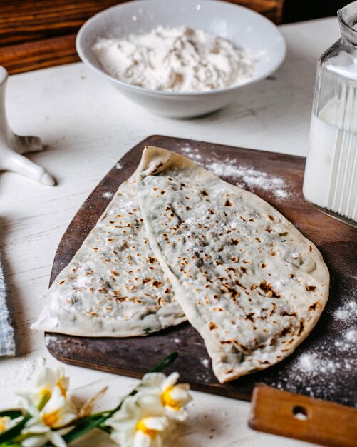 Vista lateral de la comida tradicional caucásica kutab sobre una tabla para cortar madera