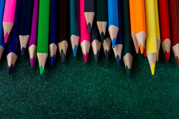 Vista lateral de un conjunto de lápices de colores en la oscuridad