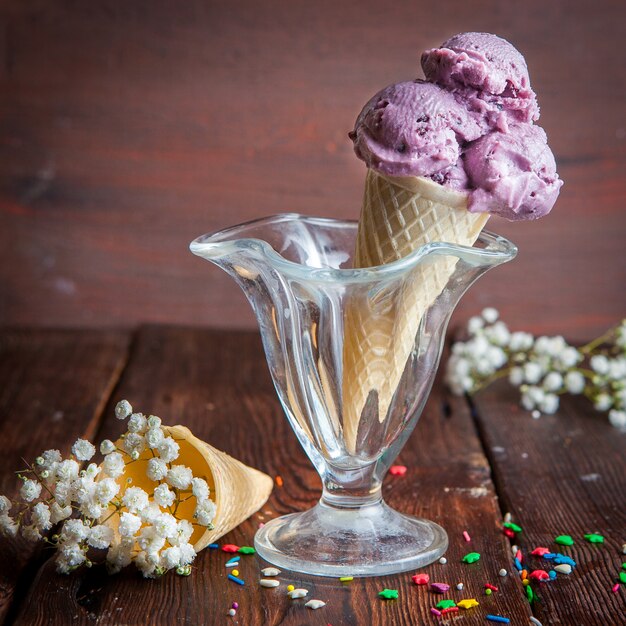 Vista lateral conos de waffle con helado de arándanos y gypsophila en copa de helado