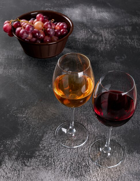 Vista lateral copas de vino con uva en piedra negra vertical