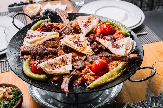 Vista lateral cordero saj costillas de cordero a la parrilla con cebolla pimiento tomate pimiento verde picante y pita con agracejo seco